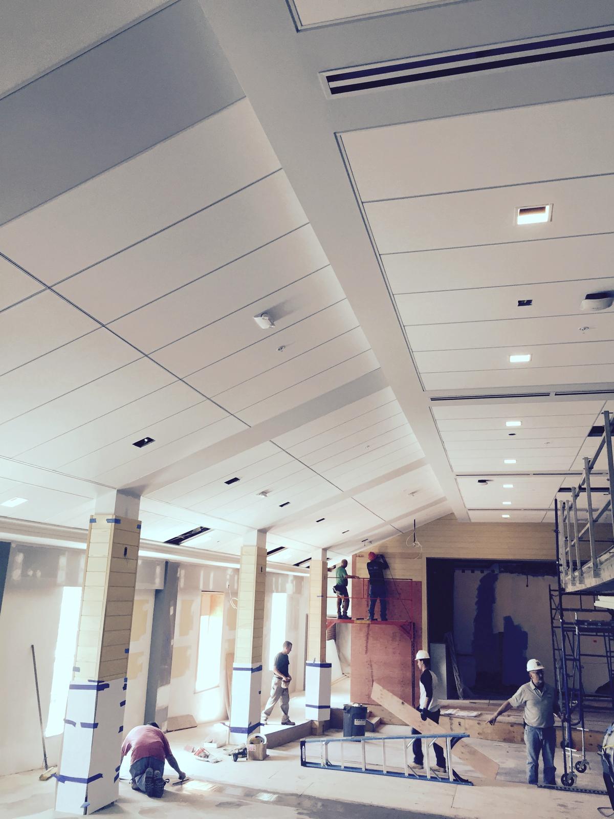 Linear plank ceiling set in coffers above a commercial lobby with columns